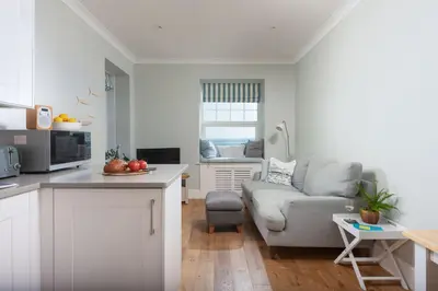 a kitchen and living room with a couch and a table at Shearwater View, 7 Rosemorran, St Ives in St Ives