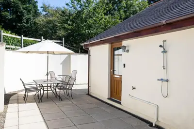 a patio with a table and chairs and an umbrella at Chy Pol in Wadebridge