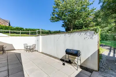 a grill on a patio next to a white fence at Chy Pol in Wadebridge