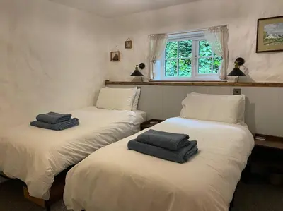 two beds in a room with towels on them at The Anvil, 2 bed cottage, in the heart of Cornwall in Gwennap