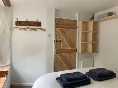 two towels sitting on a bed in a room with a door at The Anvil, 2 bed cottage, in the heart of Cornwall in Gwennap