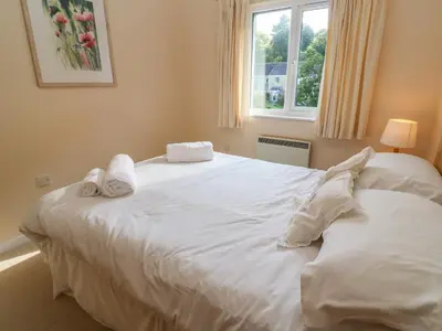 a bedroom with a large white bed with towels on it at Primrose Cottage in Falmouth