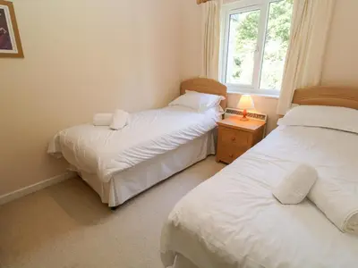 two beds in a small room with a window at Primrose Cottage in Falmouth
