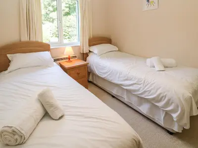 two twin beds in a room with a window at Primrose Cottage in Falmouth