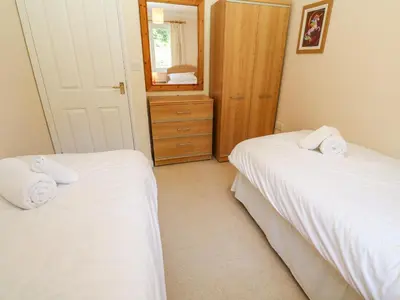 a bedroom with two beds and a mirror at Primrose Cottage in Falmouth