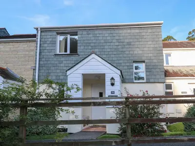 a house with a white door and a fence at Primrose Cottage in Falmouth
