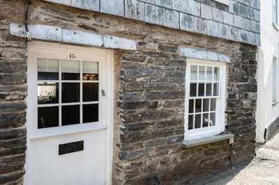 a brick building with a white door and two windows at Mobray, Port Isaac Bay Holidays in Port Isaac