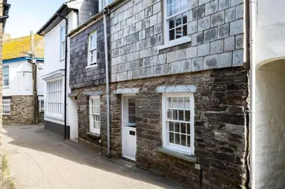 a brick building with white doors and windows on a street at Mobray, Port Isaac Bay Holidays in Port Isaac
