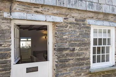 a brick building with a white door and a window at Mobray, Port Isaac Bay Holidays in Port Isaac