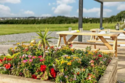a wooden picnic table and flowers in a garden at 5 Bed in St. Merryn oc-t27899 in St Merryn
