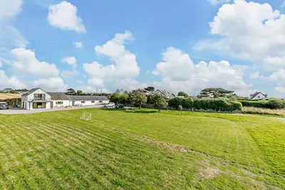 a large grass field with a house in the background at 5 Bed in St. Merryn oc-t27899 in St Merryn