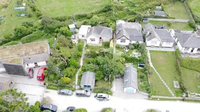 an aerial view of a house with cars parked in a parking lot at Seagulls Porthcothan Bay Cottage in Padstow