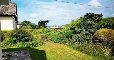 a view of a garden from the side of a house at Seagulls Porthcothan Bay Cottage in Padstow