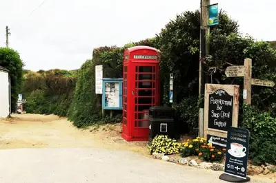 a red phone booth sitting next to a street at Seagulls Porthcothan Bay Cottage in Padstow