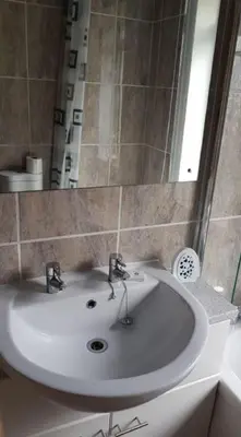 a bathroom with a white sink and a mirror at Seagulls Porthcothan Bay Cottage in Padstow