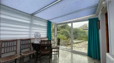 a screened in porch with a table and chairs at Seagulls Porthcothan Bay Cottage in Padstow