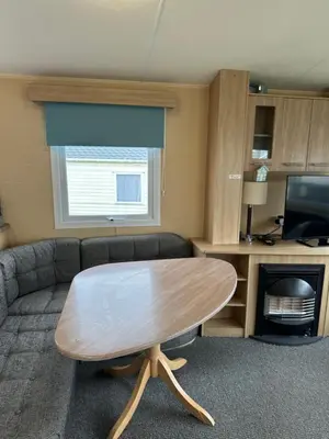 a living room with a table and a couch at Newquay Bay Porth Caravan - 8 Berth in Newquay