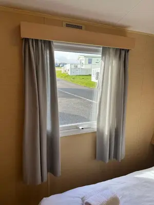 a bedroom window with a view of a street at Newquay Bay Porth Caravan - 8 Berth in Newquay