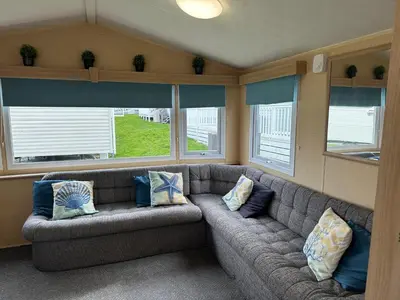 a living room with a gray couch with pillows at Newquay Bay Porth Caravan - 8 Berth in Newquay