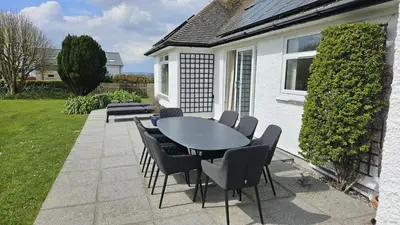 a patio with a table and chairs in a yard at Heathfield in Saint Mawes
