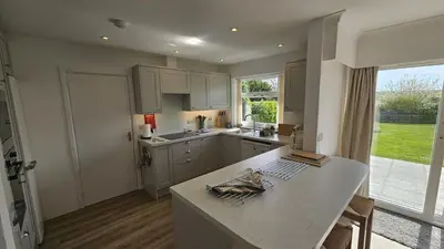 a kitchen with white cabinets and a large window at Heathfield in Saint Mawes