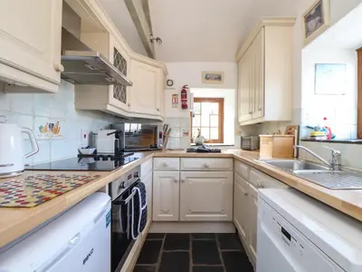 a kitchen with white cabinets and a sink at Little Riviere in Hayle