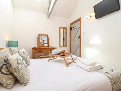 a bedroom with a white bed with a tv on the wall at Little Riviere in Hayle