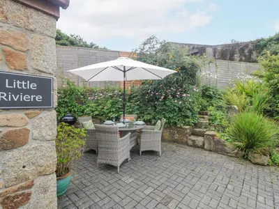 a table and chairs with an umbrella in a garden at Little Riviere in Hayle