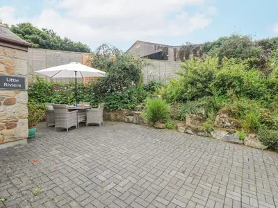 a patio with an umbrella and a table and chairs at Little Riviere in Hayle