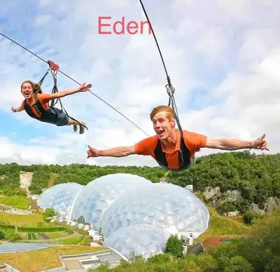 a man and a woman riding on zip lines over domes at Saint Chads Lodge Near EDEN Luxulyan in Luxulyan
