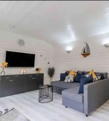 a living room with a couch and a flat screen tv at Saint Chads Lodge Near EDEN Luxulyan in Luxulyan