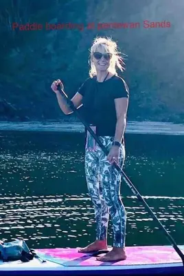 a woman standing on a paddle board in the water at Saint Chads Lodge Near EDEN Luxulyan in Luxulyan