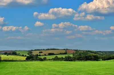 a green field with trees and clouds in the sky at Finest Retreats - The Shippon at Lestitha in Liskeard