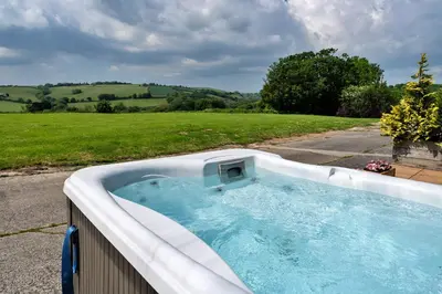 a hot tub in a backyard with a field at Finest Retreats - The Shippon at Lestitha in Liskeard
