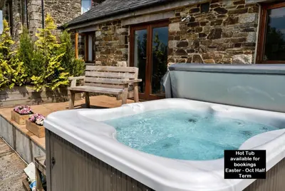a jacuzzi tub on a deck with a bench at Finest Retreats - The Shippon at Lestitha in Liskeard