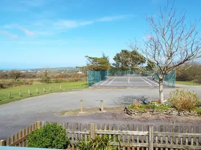 a parking lot with a tennis court in the background at The Stables - Crackington Haven Cornwall in Crackington Haven
