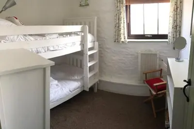 a bedroom with two bunk beds and a desk at The Stables - Crackington Haven Cornwall in Crackington Haven