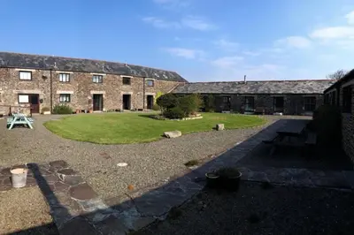 a courtyard of a large brick building with a yard at The Stables - Crackington Haven Cornwall in Crackington Haven