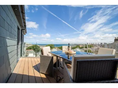 a patio with a table and chairs on a deck at Gwel An Keynvor Penthouse in Newquay
