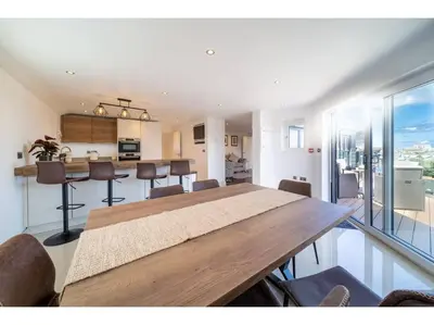 a dining room and kitchen with a large wooden table at Gwel An Keynvor Penthouse in Newquay