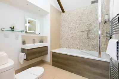a bathroom with a tub and a toilet and a sink at Carines Barns - Tre in Newquay