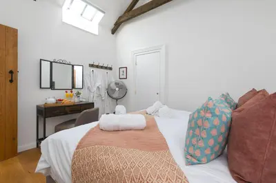 a bedroom with a white bed with a desk and a desk at Carines Barns - Tre in Newquay