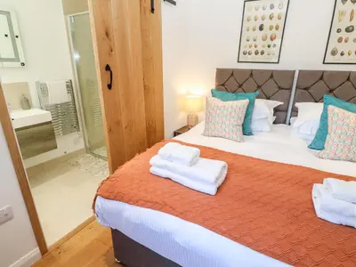 a bedroom with a large bed with towels on it at Carines Barns - Pol in Newquay
