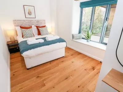 a bedroom with a bed and two windows at Carines Barns - Pol in Newquay
