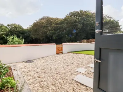 a door to a garden with a white fence at Carines Barns - Pol in Newquay