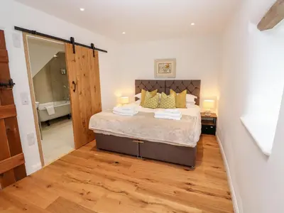a bedroom with a large bed with yellow pillows at Carines Barns - Par in Newquay