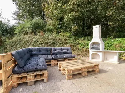 a blue couch sitting next to a wooden table at Carines Barns - Par in Newquay