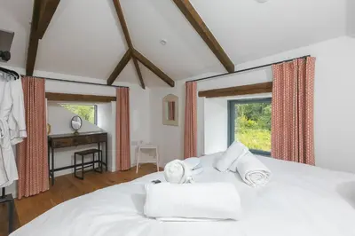 a bedroom with a white bed with towels on it at Carines Barns - Pen in Newquay