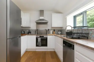 a kitchen with white cabinets and a stainless steel refrigerator at Carines Barns - Pen in Newquay