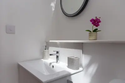 a white bathroom with a sink and a mirror at Carines Barns - Pen in Newquay